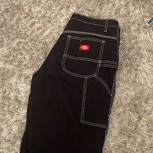 Low waisted black utility pants with white stitching.